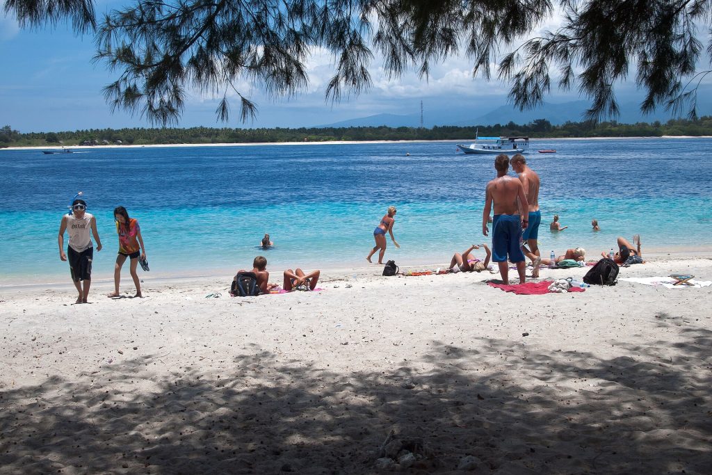 Uimareita ja auringonottajia Gili Trawanganin valkoisella hiekkarannalla