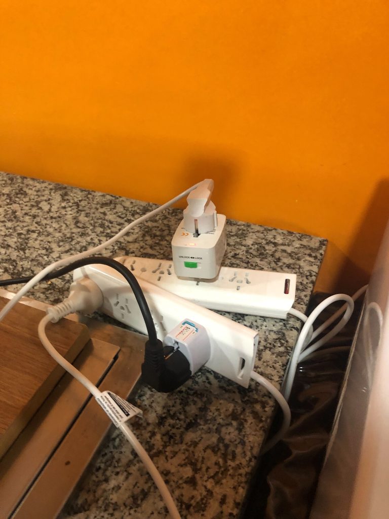 Matka-adaptereita ja jatkojohto pistorasiassa hotellihuoneessa