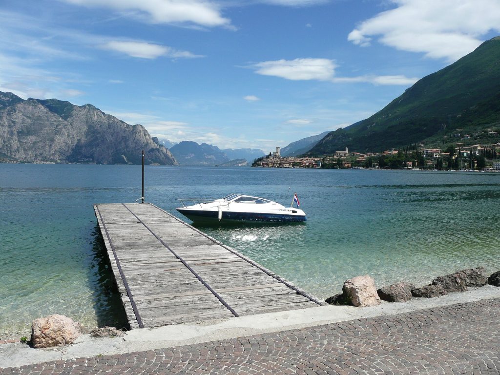 Laituri ja vene Malcesinen rannassa, taustalla vuorten ympäröimä Gardajärvi