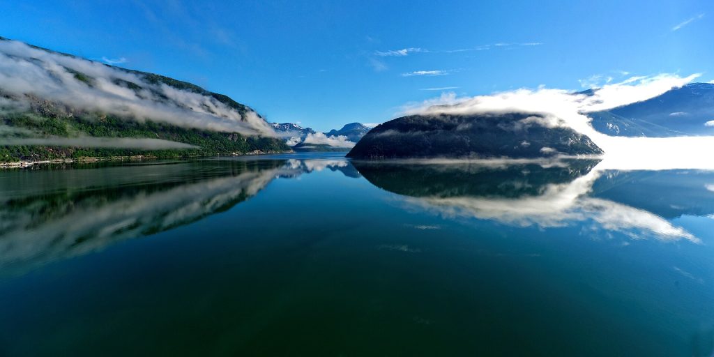Tyyni Hardangerfjord ja lumihuippuiset vuoret heijastuvat vedestä aamulla