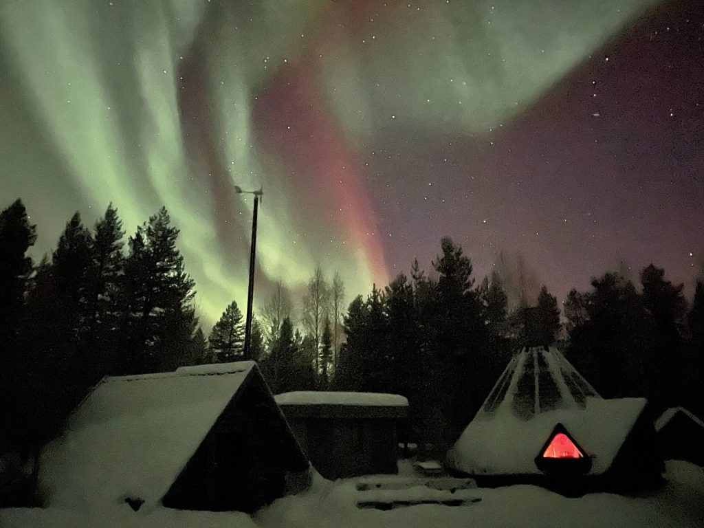 Revontulet lumisen grillikodan yllä Pellossa Lapissa