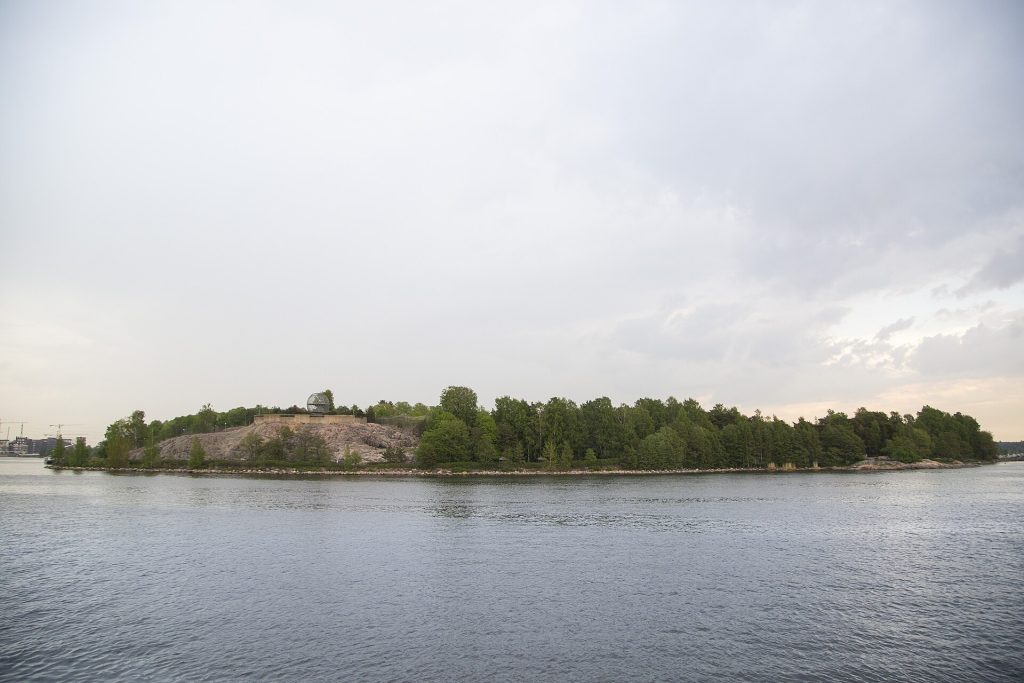 Korkeasaaren metsäinen saari ja rantakalliot mereltä nähtynä