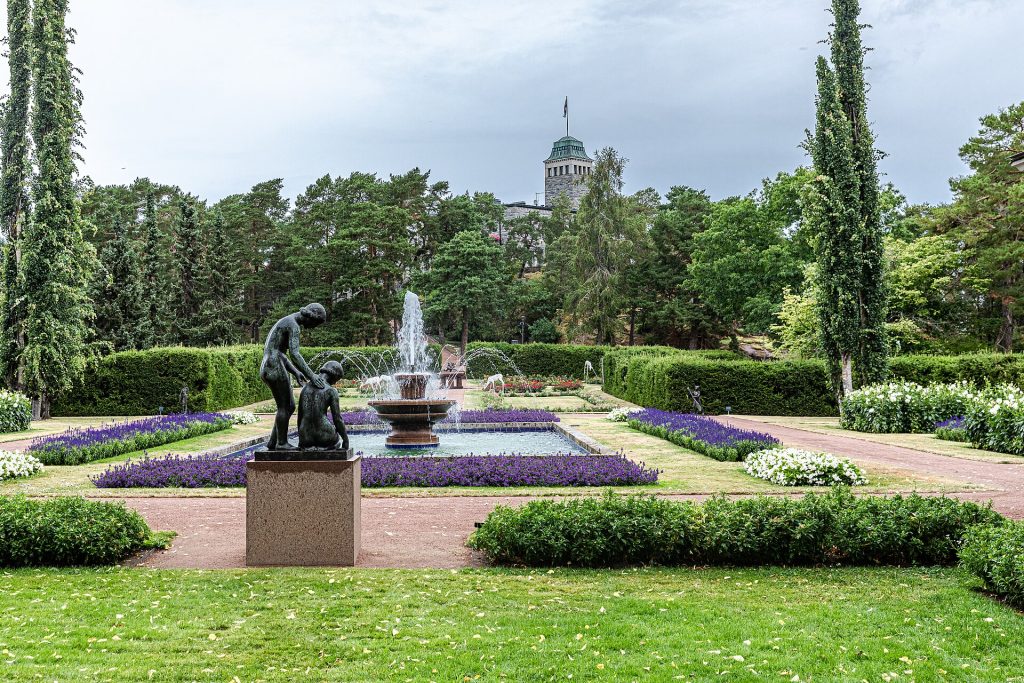 Kultarannan puutarhan kukkaistutuksia ja suihkulähde, taustalla graniittilinna