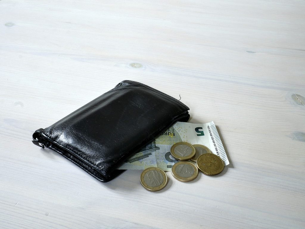 Lompakko, eurosetelit ja kolikot pöydällä