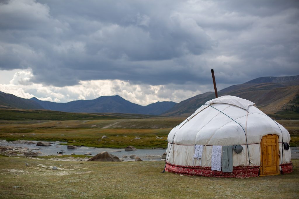 Paimentolaisperheen valkoinen ger-teltta vuorten ympäröimällä aroalueella Länsi-Mongoliassa