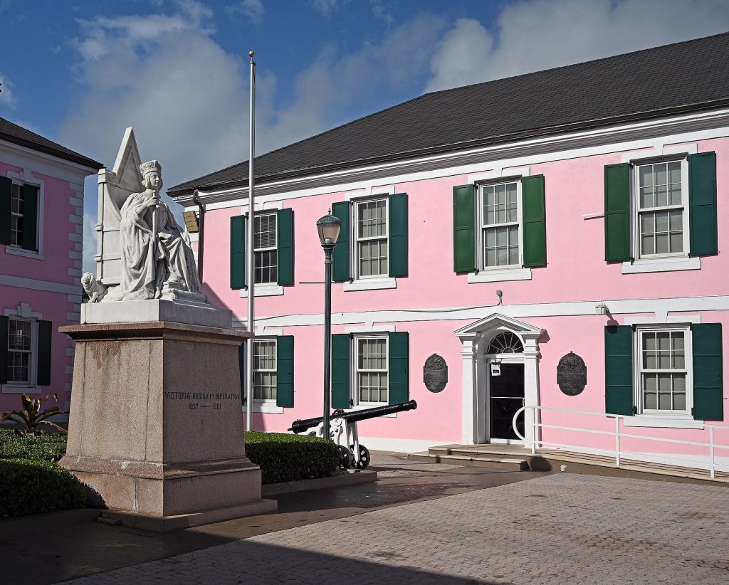 Vaaleanpunainen parlamenttitalo ja kuningatar Victorian patsas Parliament Squarella Nassaussa