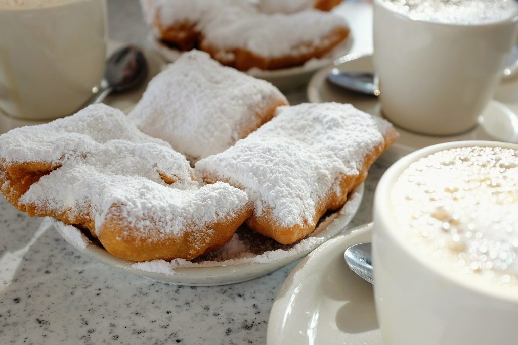 Tomusokerilla päällystettyjä beignet-munkkeja ja café au lait Café du Mondessa New Orleansissa