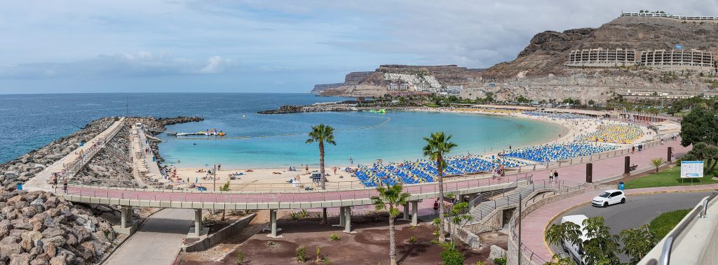 Aallonmurtajien suojaama Playa de Amadoresin hiekkaranta ja turkoosi meri Gran Canarialla