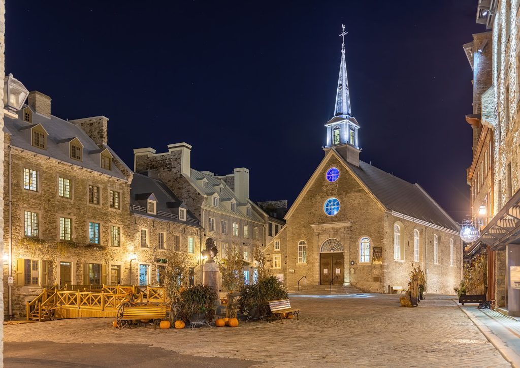 Place Royale -aukio ja Notre-Dame-des-Victoiresin kivikirkko iltavalaistuksessa Québecin alakaupungissa