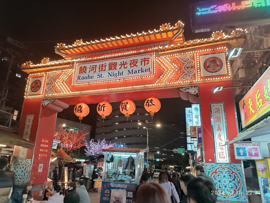 Raohen yötorin valaistu porttikaari ja ruokakojuja illalla Taipeissa