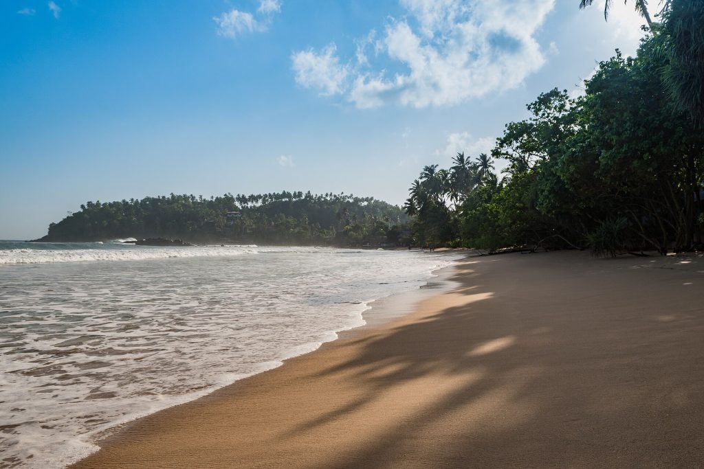 Mirissan hiekkaranta ja vehreä niemi Sri Lankan etelärannikolla