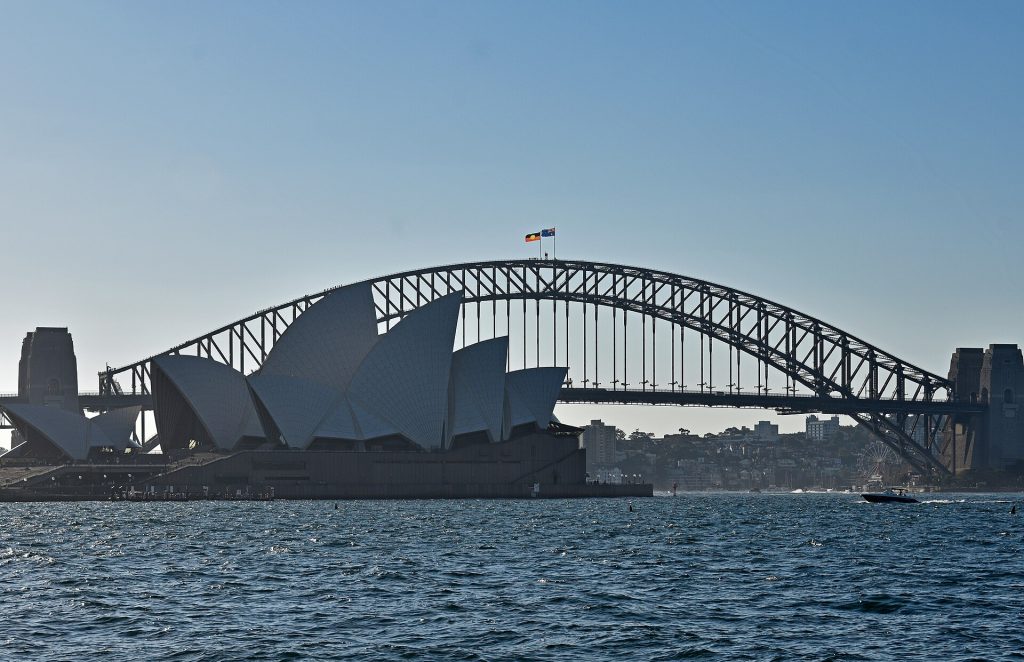 Sydneyn oopperatalon kuorimaiset katot ja Harbour Bridge -silta sataman rannalta